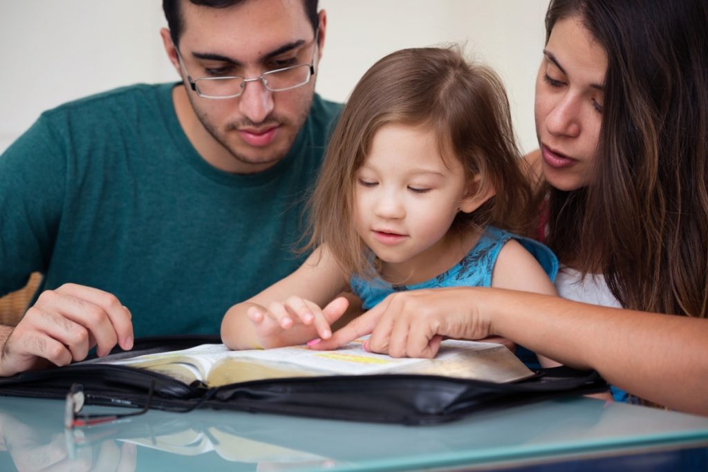 Parents reading with their daughter